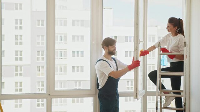 Employees of a cleaning company clean a house or apartment. A man and a woman wash windows in an apartment after repairs. Cleaning an apartment or house. The family cleans the windows.
