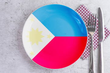 Naklejka premium A Plate with the Flag of Philippines, Cutlery and Napkins on the Mable Table.