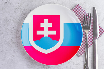 A Plate with the Flag of Slovakia, Cutlery and Napkins on the Mable Table.