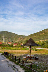 Fototapeta premium Small outdoors rural rest place with wooden umbrella, benches and a table. Beautiful green hills of a mountain in the background. Western Serbia, Balkans