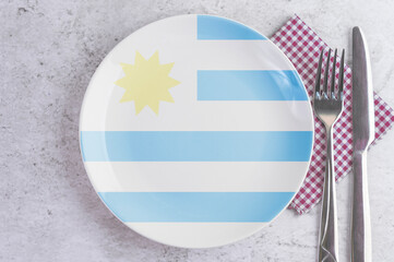A Plate with the Flag of Uruguay, Cutlery and Napkins on the Mable Table.