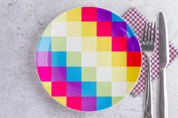 A Plate with the Flag of Wiphala, Cutlery and Napkins on the Mable Table.