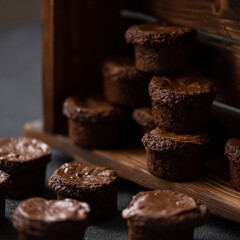 Chocolate fondants. French dessert. Chocolate pastry. Fondanas on wooden shelf. Dark background. Side view. Soft focus.