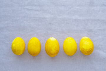 Natural dyed yellow colored eggs on neutral background, top view, flat lay. Happy Easter. Copy space for text.