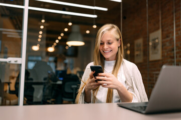 Businesswoman holding a mobile phone, chatting with someone.
