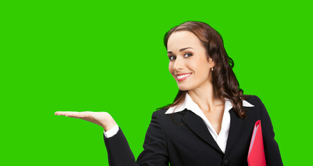 Portrait image of happy smiling business woman in confident suit showing, giving, holding, advertising. Executive worker, teacher or real estate agent with folder. Green chroma key background.