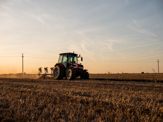 Tractor plowing and preparing stubble field for crop seeding