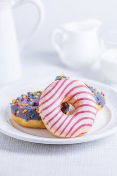 American donuts on white plate on bright background. Playful and colourful image of sweets and desserts. 