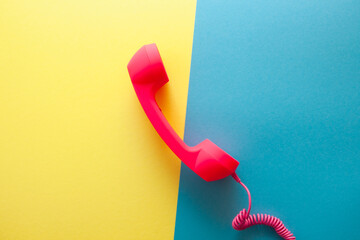 Pink phone or handset on yellow and blue background, card with communication and talking concept