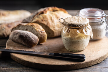 Rye sourdough ripened in a jar together with fresh bread on a cutting board