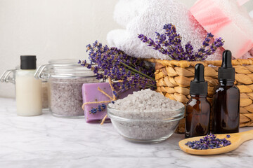 Lavender spa. Cosmetic products sea salt, body cream, scrub, essential oils and lavender flowers on a marble background.Natural herb cosmetic with lavender flowers. Beauty concept. Copy space.