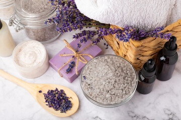 Lavender spa. Cosmetic products sea salt, body cream, scrub, essential oils and lavender flowers on a marble background.Natural herb cosmetic with lavender flowers. Beauty concept. Copy space.
