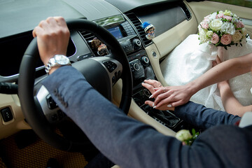bride and groom holding hands while sitting in the car on their wedding day