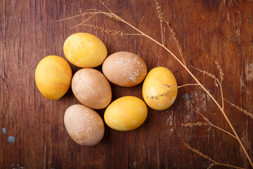 Brown and yellow Easter eggs on rustic table, colored with coffee and turmeric. Happy Easter concept, top view.