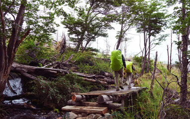 back view of couple of hikers walking on a small bridge doing the 