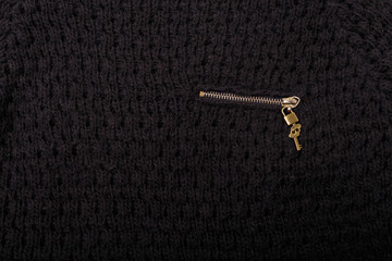 Metallic zipper, lock and key on knitted black cloth background