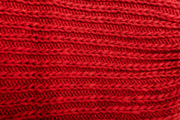 Knit red fabric texture, background or backdrop. Textile, scarf or sweater textured surface. Warm accessories, clothing, fashion concept