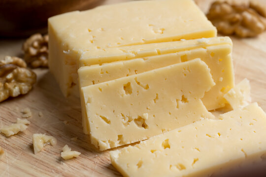 Sliced hard cheese with holes and walnuts - Powered by Adobe