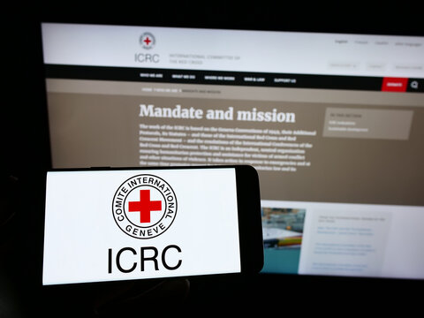 Stuttgart, Germany - 01-21-2023: Person holding smartphone with logo of International Committee of the Red Cross (ICRC) on screen in front of website. Focus on phone display.