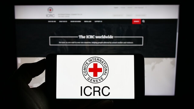 Stuttgart, Germany - 01-21-2023: Person holding cellphone with logo of International Committee of the Red Cross (ICRC) on screen in front of webpage. Focus on phone display.