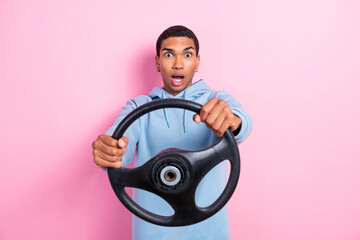 Photo of young surprised shocked confused man first time car driving hold steering wheel dangerous speed crime isolated on pink color background