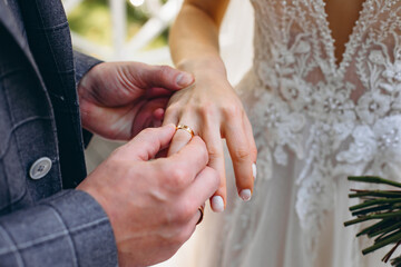 Married couple exchange wedding rings at Indonesian wedding ceremony. Groom put a ring on finger of...