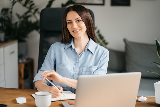Young happy smiling professional business woman, female company worker or corporate manager posing in modern office working, looking at camera, portrait.