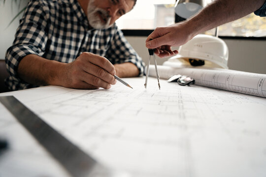 Architects engineer discussing at the table with blueprint - Closeup on hands and project print.