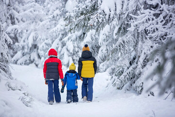 Fototapeta na wymiar Sweet happy children, brothers, playing in deep snow in forest, frosted trees