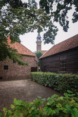 Empty courtyard between old houses overlooking the old church tower. - 564677227