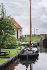 Traditional Dutch fishing boat with picturesque fishermen's cottages in the background in the historic town of Enkhuizen, The Netherlands.