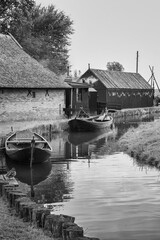Small canal with its traditional fishing boats, fish smoker in the background. - 564677436
