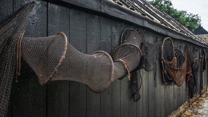 A fishing net dries against a black tarred fence.