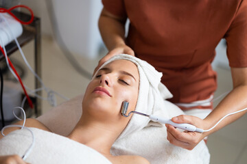 Obraz na płótnie Canvas Tools facial mask treatment. Beautiful caucasian woman getting face massage in beauty spa and wellness center. Facial treatment and skin care concept.