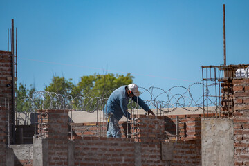 Bricklayer laying mud bricks in house construction in Argentina.