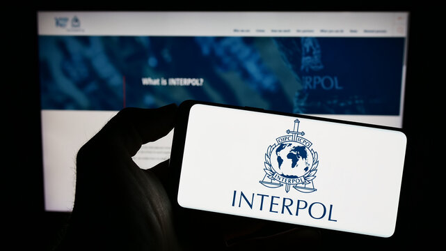 Stuttgart, Germany - 01-22-2023: Person holding smartphone with logo of International Criminal Police Organization (ICPO) on screen in front of website. Focus on phone display.