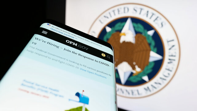 Stuttgart, Germany - 01-22-2023: Smartphone with website of US Office of Personnel Management (OPM) on screen in front of seal. Focus on top-left of phone display.