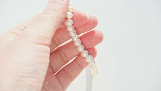 close up a river pearl bracelet in the hands of a woman. she touches it and twists it on her fingers. white background. High quality FullHD footage with slow motion