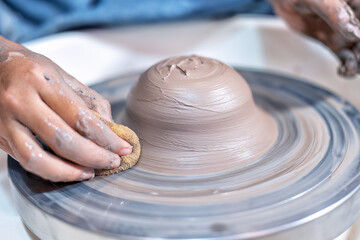 Close up hands make dishes from ceramic clay working on potters wheel traditional pottery craft