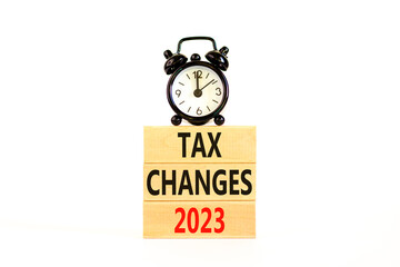 Tax changes 2023 symbol. Concept words Tax changes 2023 on wooden blocks on a beautiful white table white background. Black alarm clock. Business Tax changes 2023 concept. Copy space.