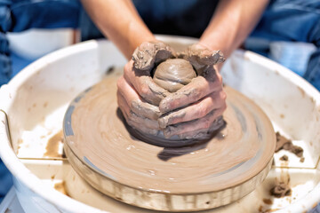 Close up hands make dishes from ceramic clay working on potters wheel traditional pottery craft