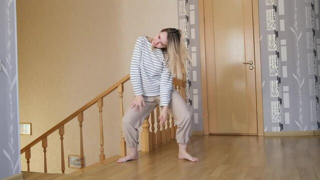 Girl fools around in bright apartment, joy, antics, crab dance. Moving to a new apartment, completion of repairs. Foolish funny dance against the staircase. High quality slow motion FullHD footage 