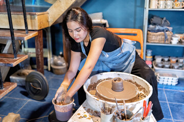 Women learn to make clay pot on potters wheel making ceramic clay objects in pottery workshop