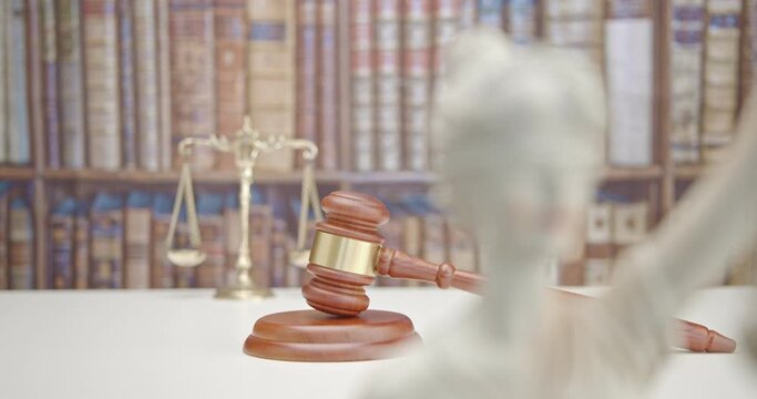 Legal office of lawyers, justice and law concept : Judge's gavel or hammer and base used by a judge person on a desk in a courtroom with blurred books and a bookshelf or bookcase in the background.