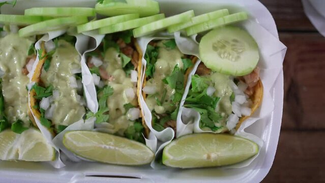 Slow motion savory look at street tacos with guacamole sauce on a plate