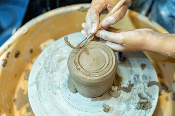 Close up hands make dishes from ceramic clay working on potters wheel traditional pottery craft
