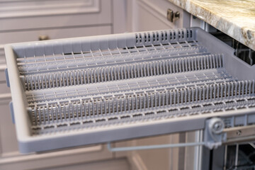 Open tray of dishwasher. Close up view of household appliances in kitchen
