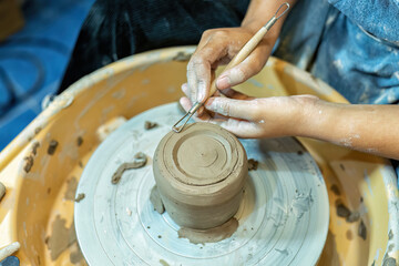 Close up hands make dishes from ceramic clay working on potters wheel traditional pottery craft