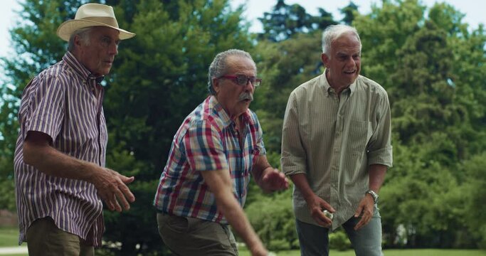 Portrait of Cheerful Senior Retired Friends Having Fun, Playing a Friendly Game of Boules and Laughing Together in the Park. A Group of Elderly Being Active and Enjoying the Good Summer Weather 