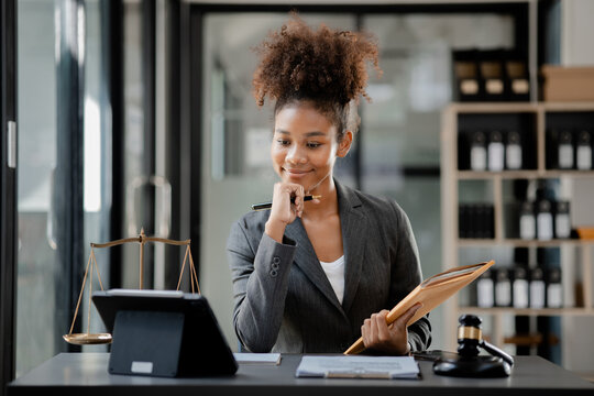 American Lawyer Sits In A Law Firm, Female Lawyer Holding A Contract Document Serving A Client In A Court Case. The Concept Of Justice Law.